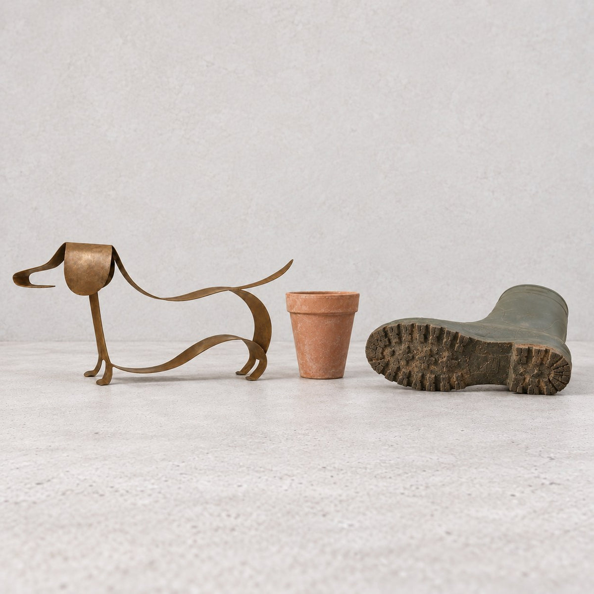 LoyalPaw sculpture next to a terracotta pot and a garden boot for scale